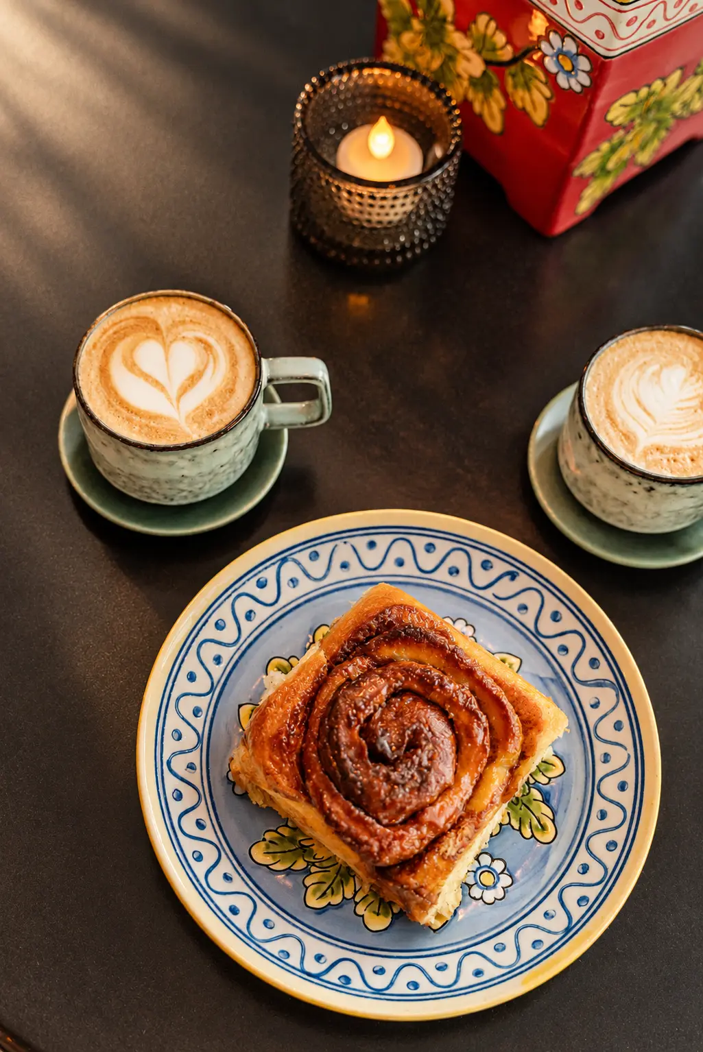 Kanelsnegl og to flat whites på bordet